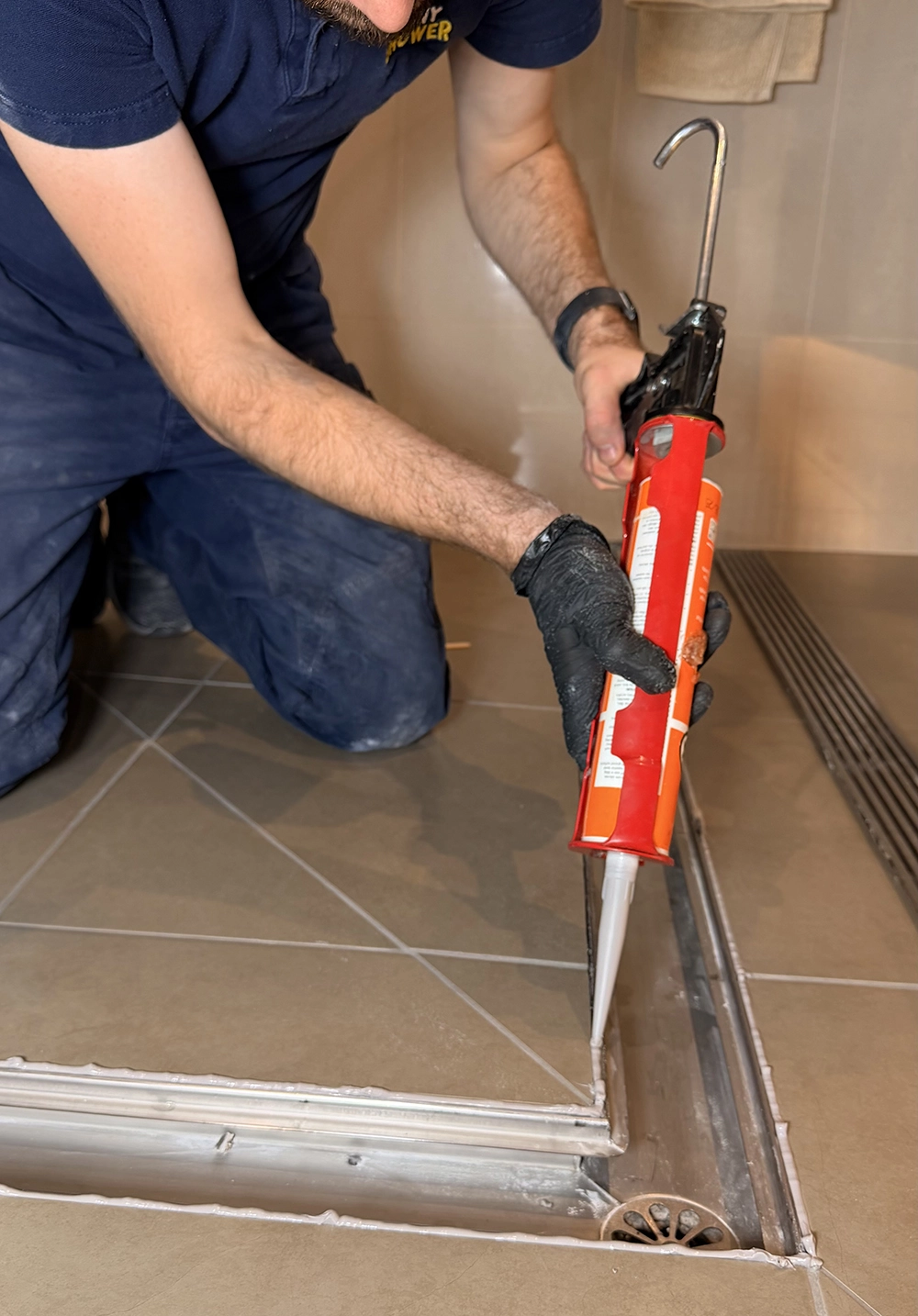 Shiny Shower specialist inspecting the base of a shower for signs of a leaking shower