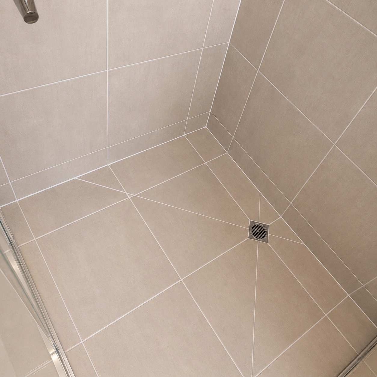 Applying grout to shower base tiles using a grout float during tile repair