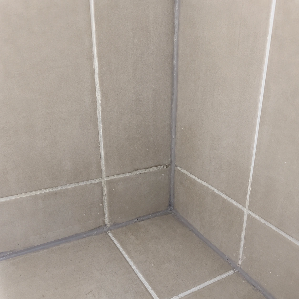 Technician inspecting shower tiles and joints for leak damage