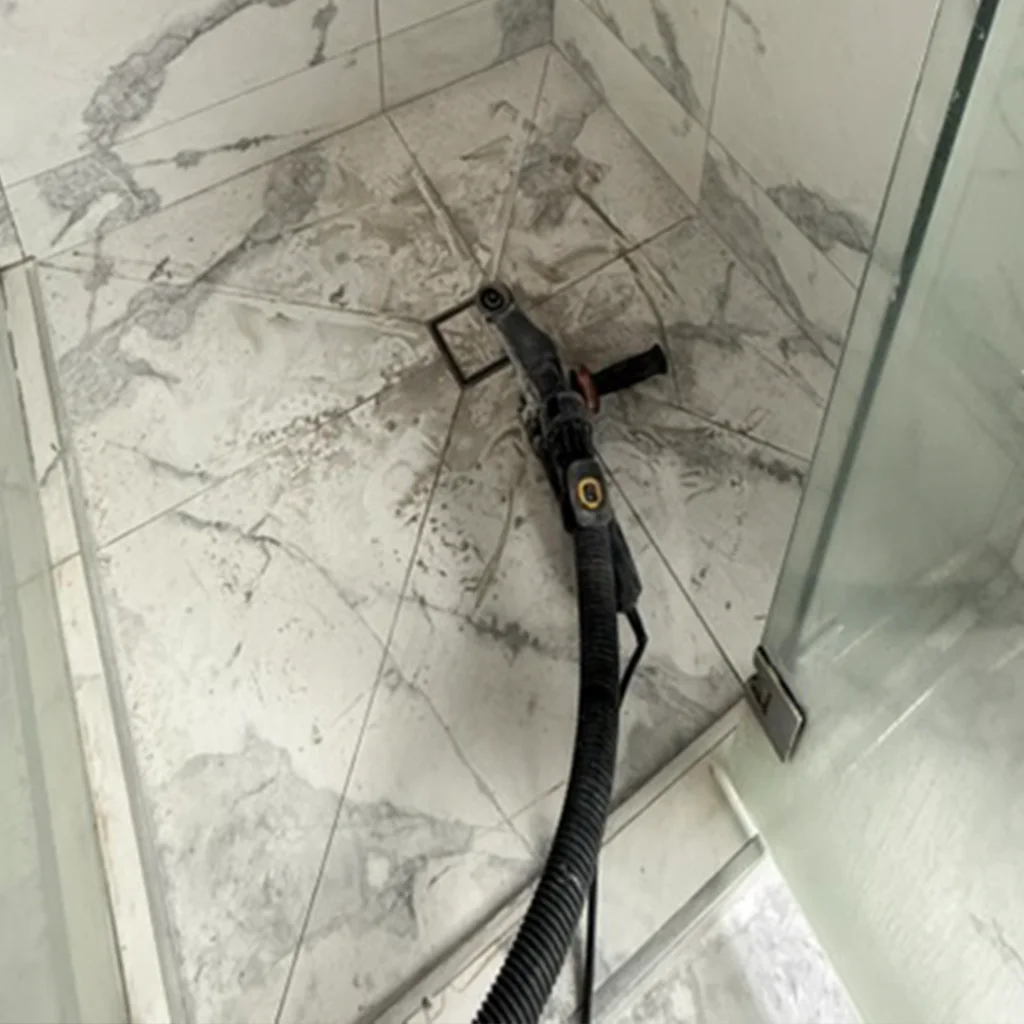Removing old grout and silicone from shower joints before repair